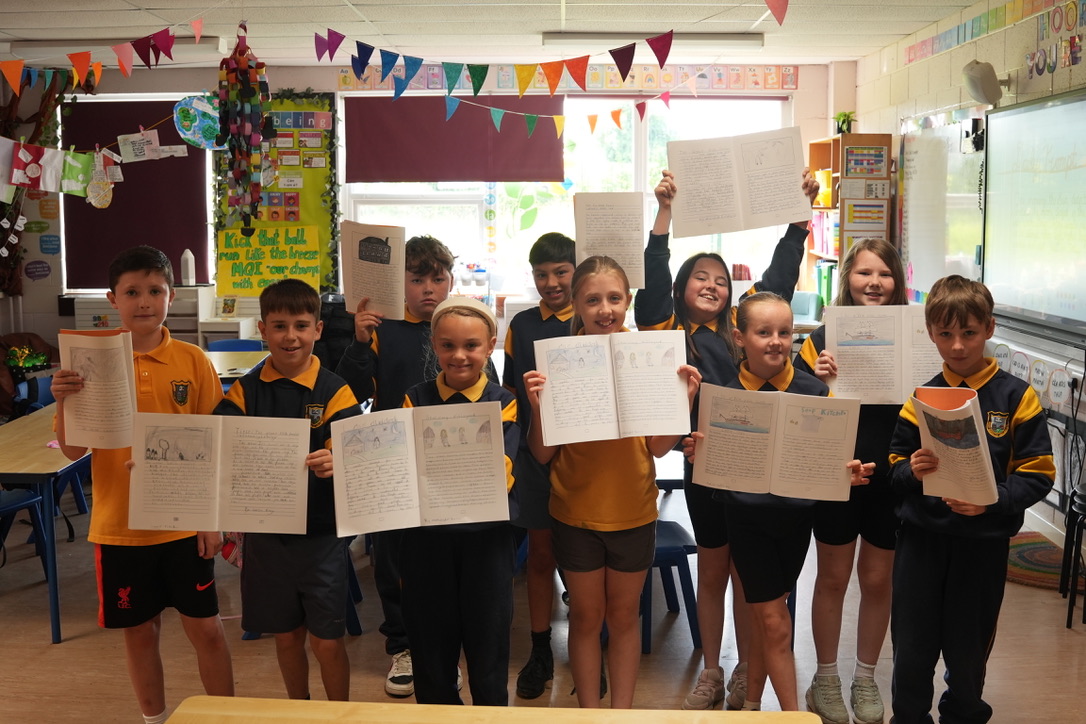 Primary school pupil holding published class book with illustrations and story